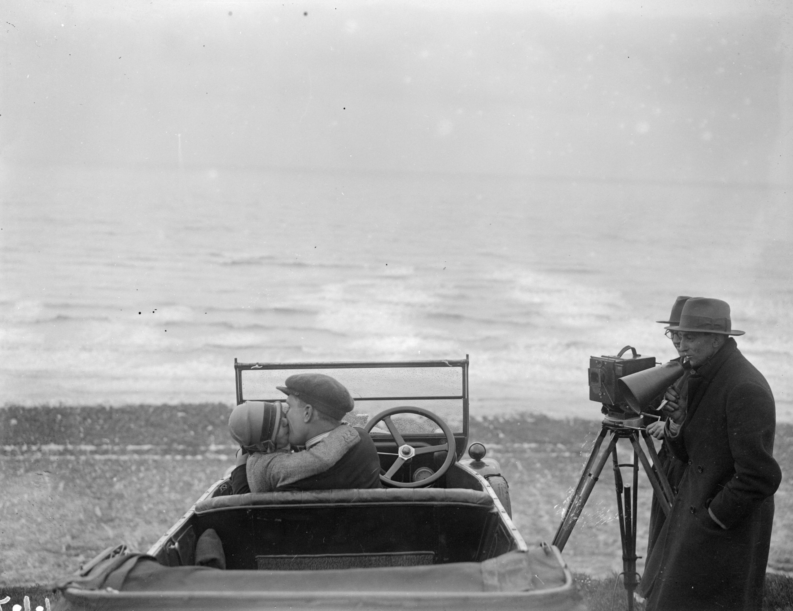 A couple in an open car locked in a passionate embrace for a scene in the film, The Thrill, being shot on Brighton beach.