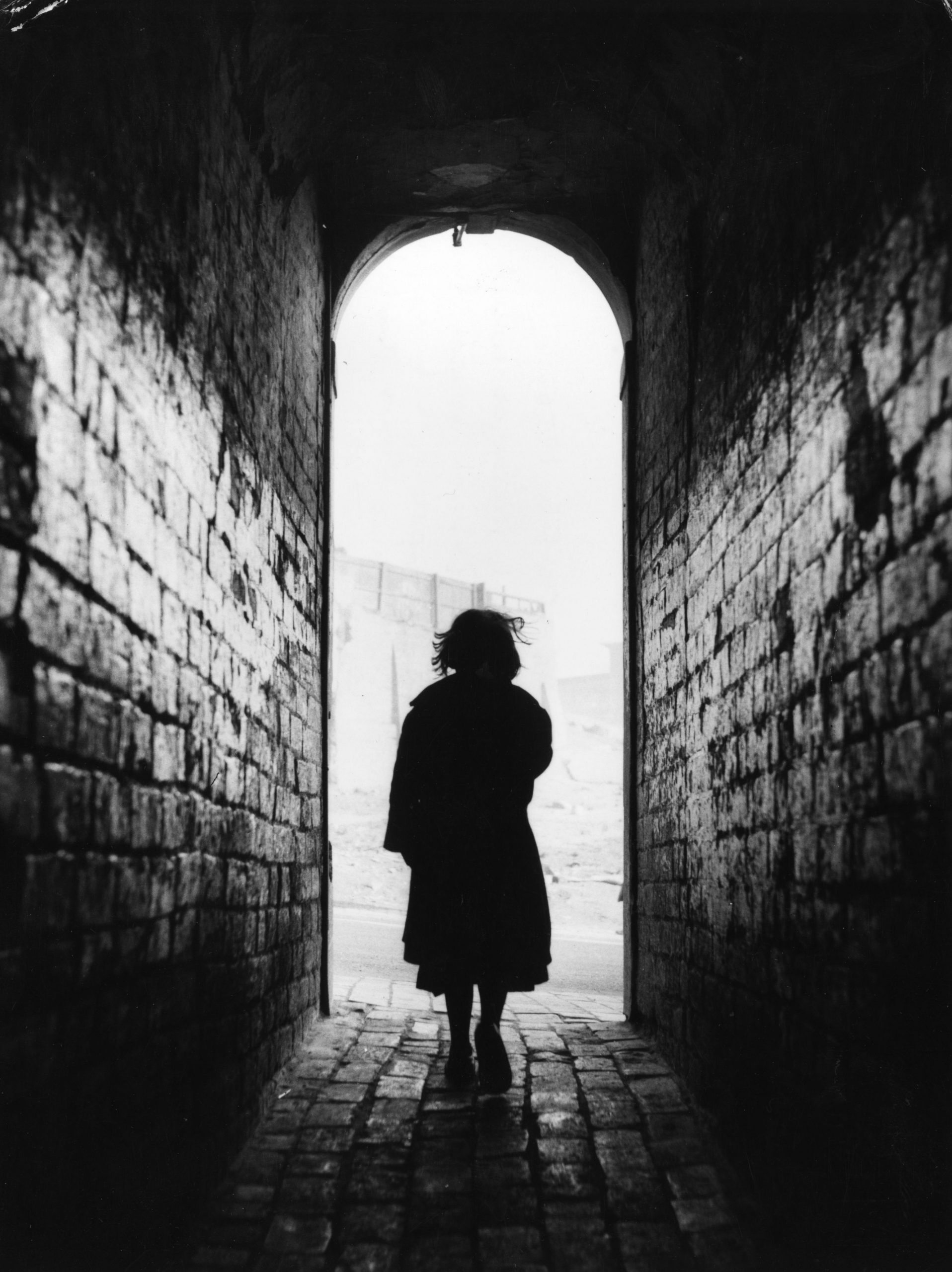 A silhouetted figure in a dark passage
