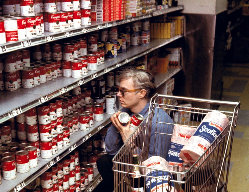 Warhol shops for Campbell’s Soup at a Gristedes Market.