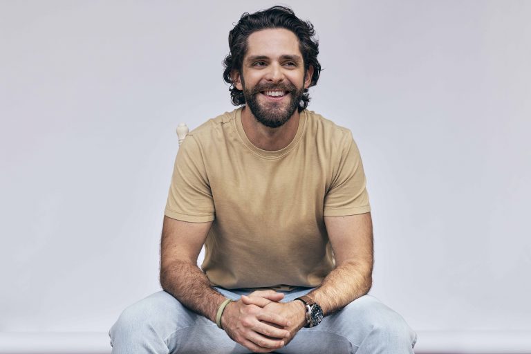 Thomas Rhett sitting in a chair smiling
