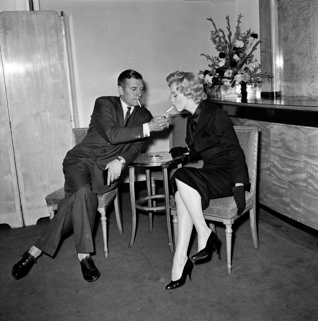 17th July 1956: American film star Marilyn Monroe (1926 - 1962) accepts a light from British thespian Laurence Olivier (1907 - 1989) at a press conference at the Savoy Hotel, London. (Photo by Harry Kerr/BIPs/Getty Images)